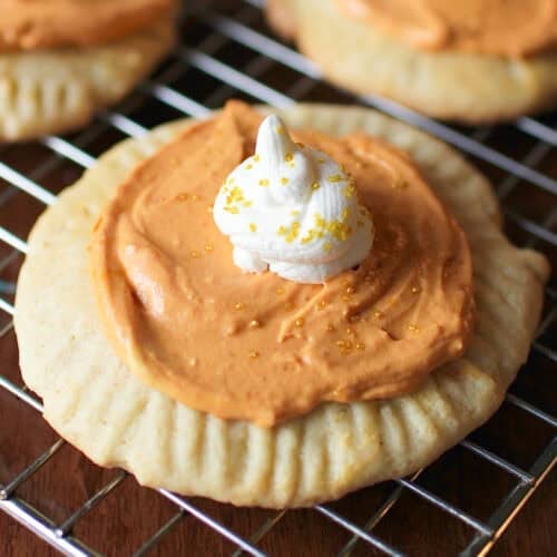 a pumpkin sugar cookie topped with pumpkin frosting and whipped cream.