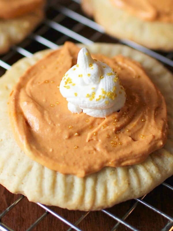 a pumpkin sugar cookie topped with pumpkin frosting and whipped cream.
