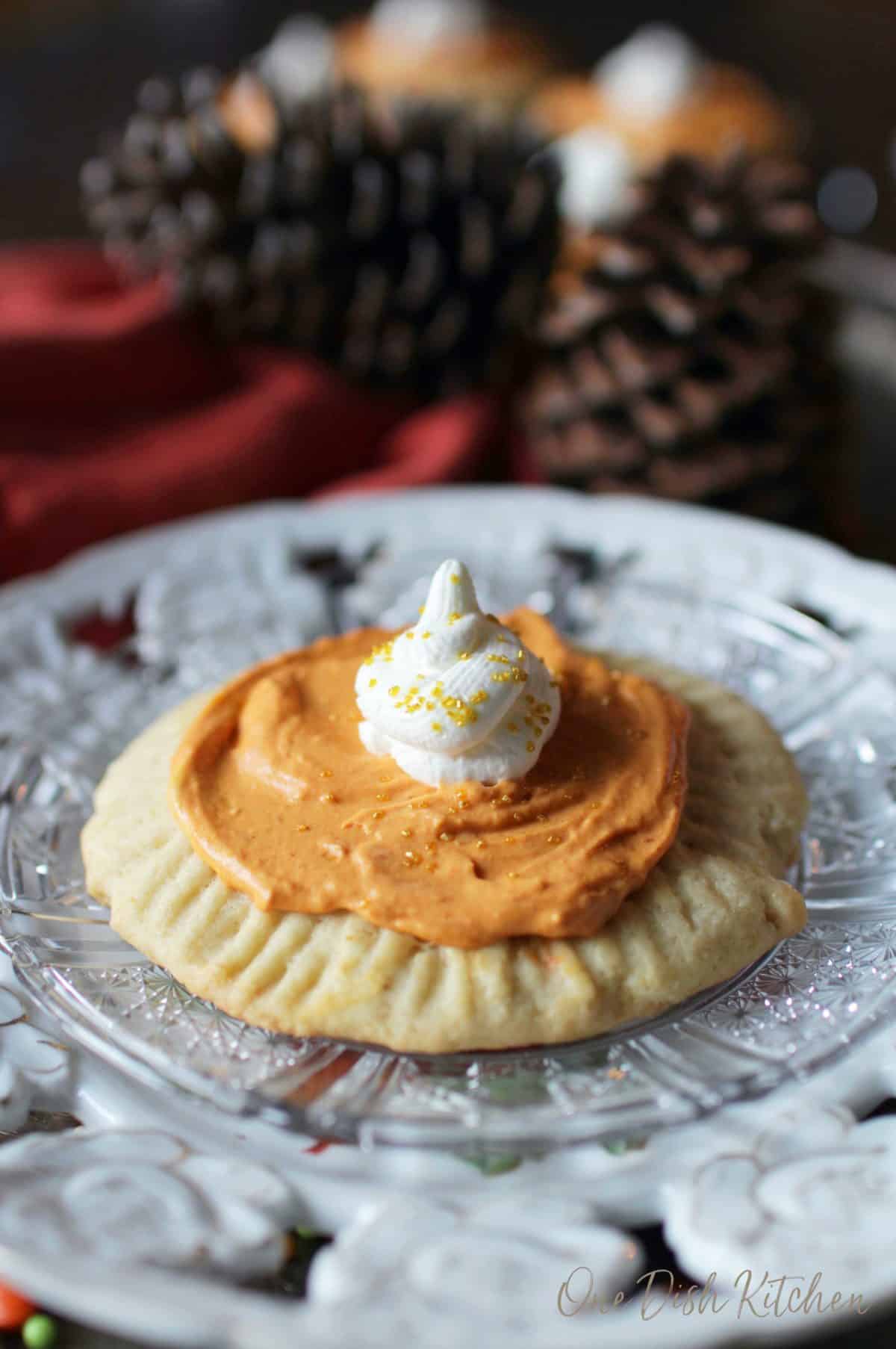 a sugar cookie topped with orange pumpkin filling and a scoop of whipped cream.