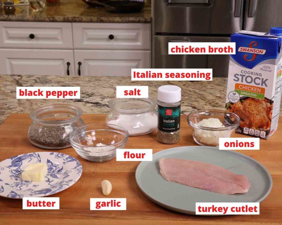 a turkey cutlet, butter, onions, broth, flour and seasonings on a wooden cutting board.