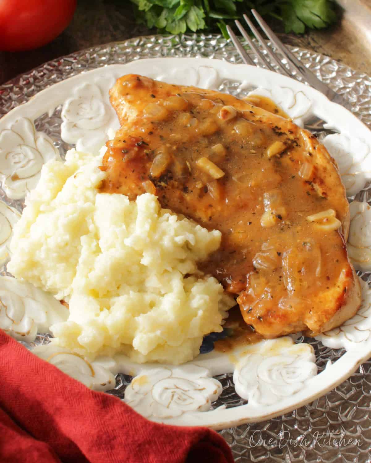 a single pan seared turkey cutlet with gravy next to mashed potatoes on a white plate.