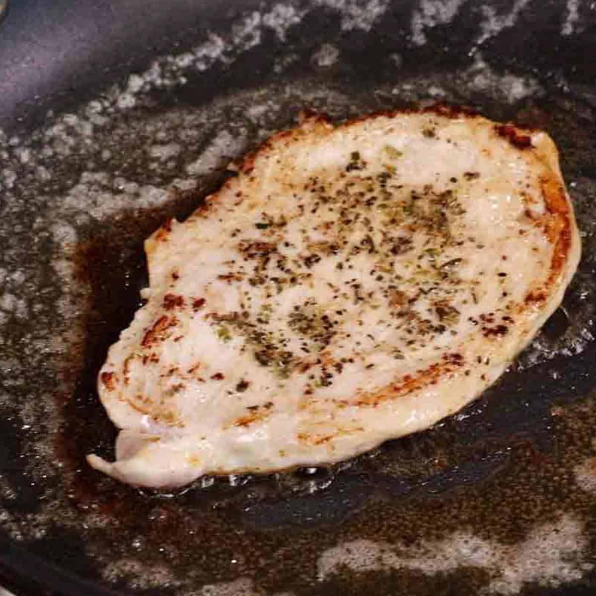 a seasoned turkey cutlet in a skillet.