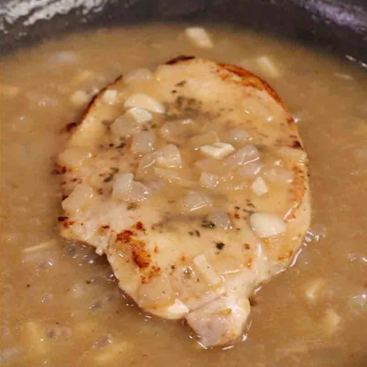 a turkey cutlet with gravy in a skillet.