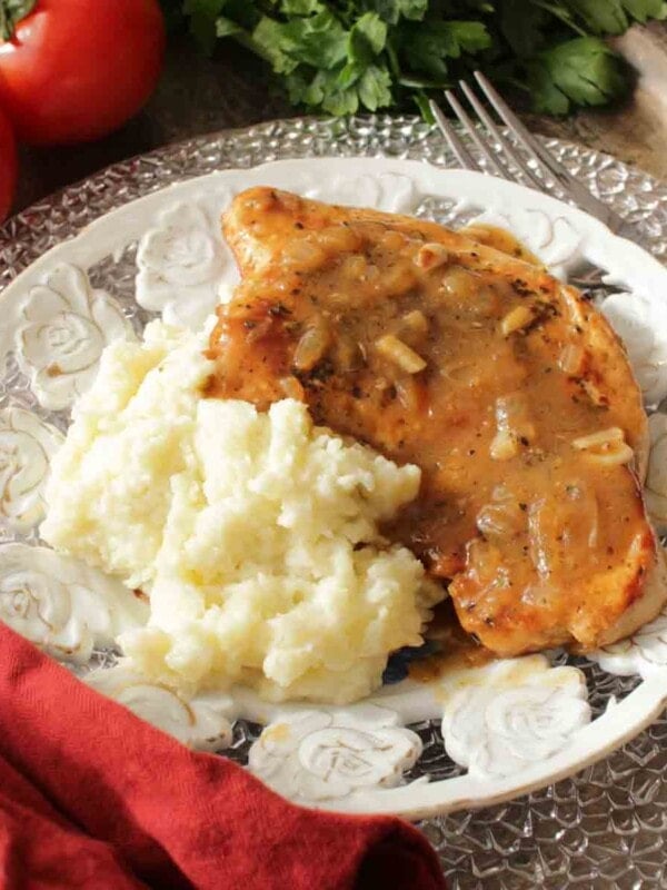 a turkey cutlet on a white plate next to mashed potatoes
