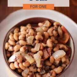 a small bowl of black eyed peas with bacon and onions on a table.