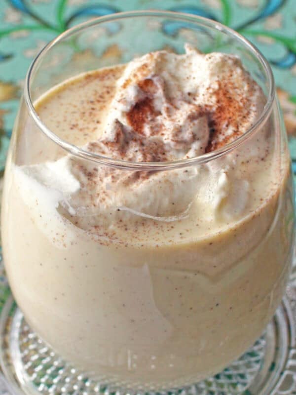 a single serving of eggnog in a glass topped with whipped cream.