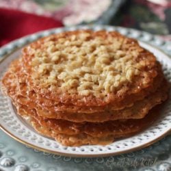 five florentine lace cookies stacked on a white plate next to a red napkin