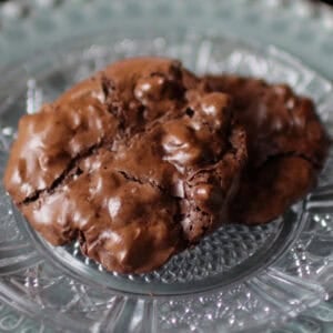 two flourless chocolate cookies on a green plate.
