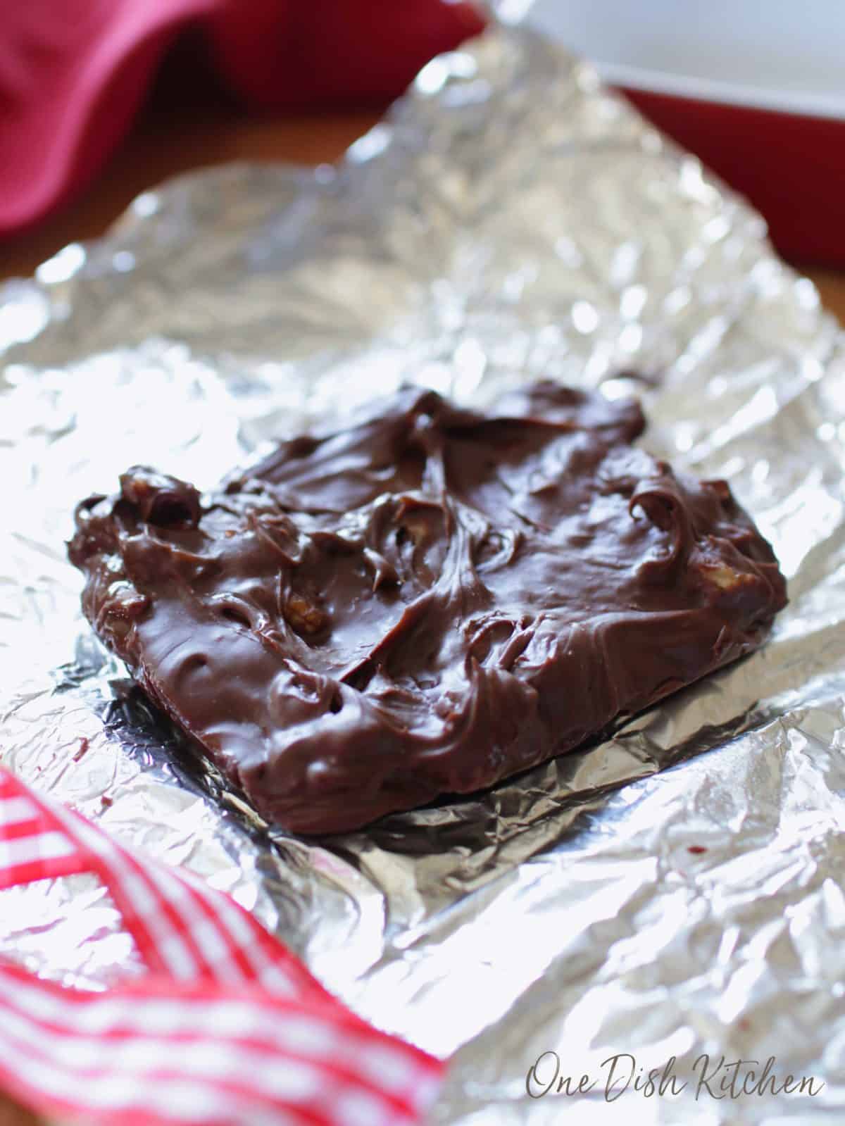 a large square of fudge on a sheet of aluminum foil next to a red ribbon.