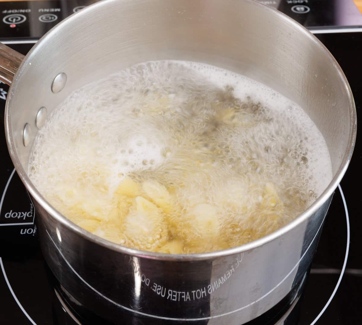 penne pasta cooking in boiling water in a pot on the stove
