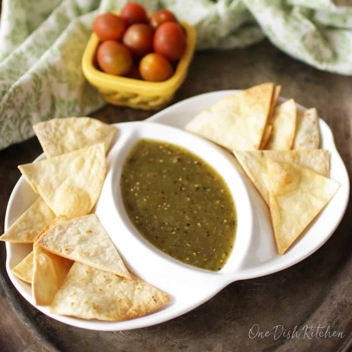 a small batch of homemade tortilla chips on a plate with dip.