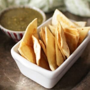 a single serving of homemade baked tortilla chips in a bowl next to salsa.