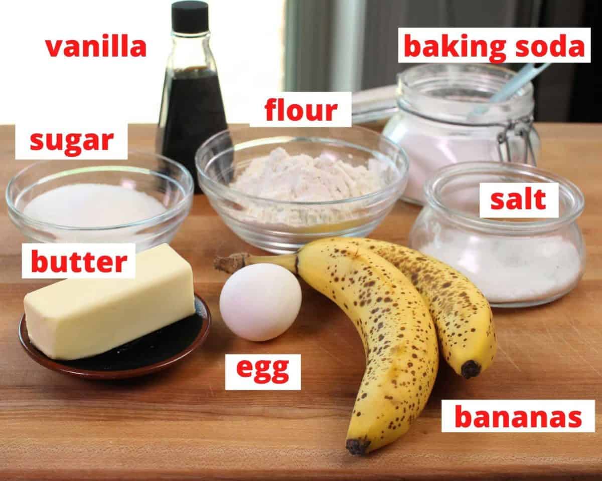 the ingredients used in banana muffins on a brown wooden cutting board.
