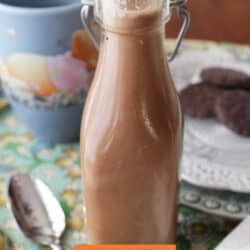 a small jar of chocolate coffee creamer next to a plate of chocolate cookies.