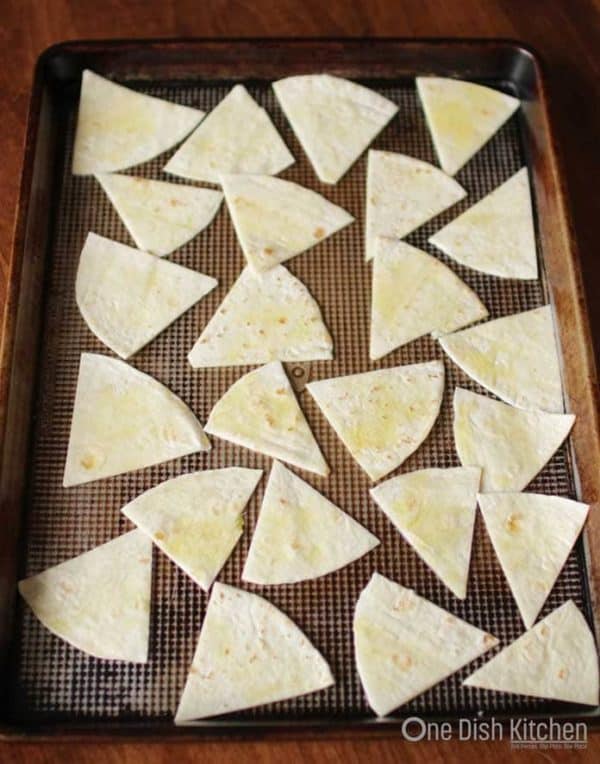 tortilla wedges placed on a baking pan ready to go into the oven