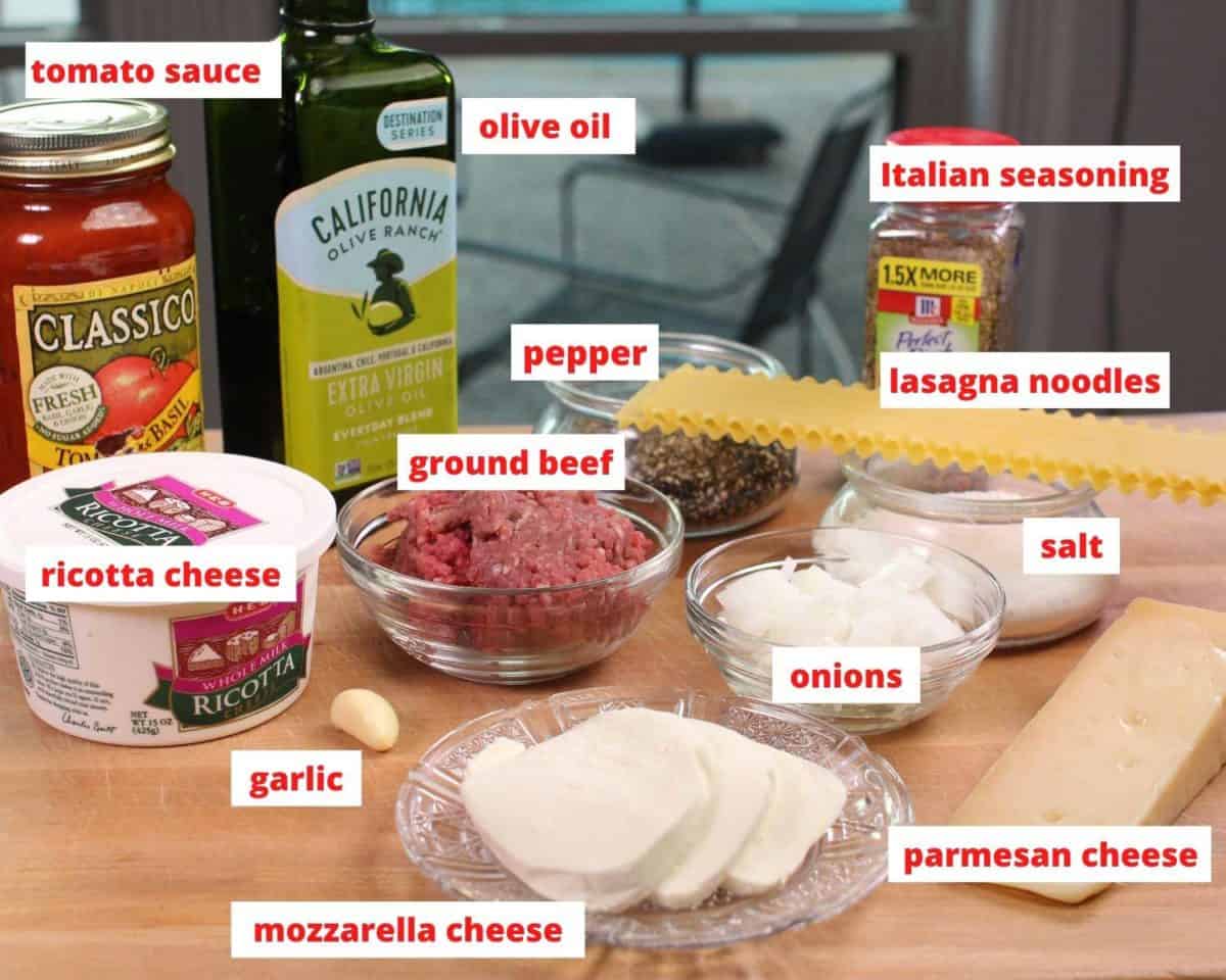 the ingredients needed to make lasagna labeled on a brown table.