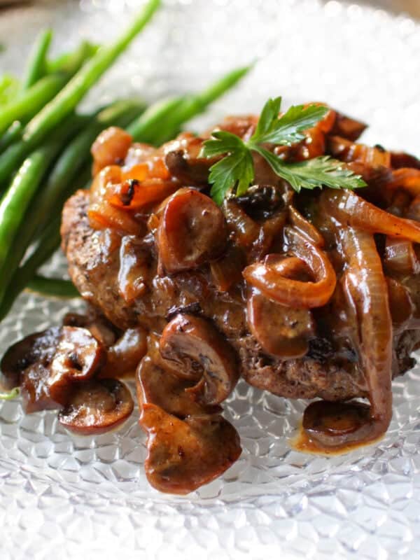 Salisbury Steak on a plate with green beans.
