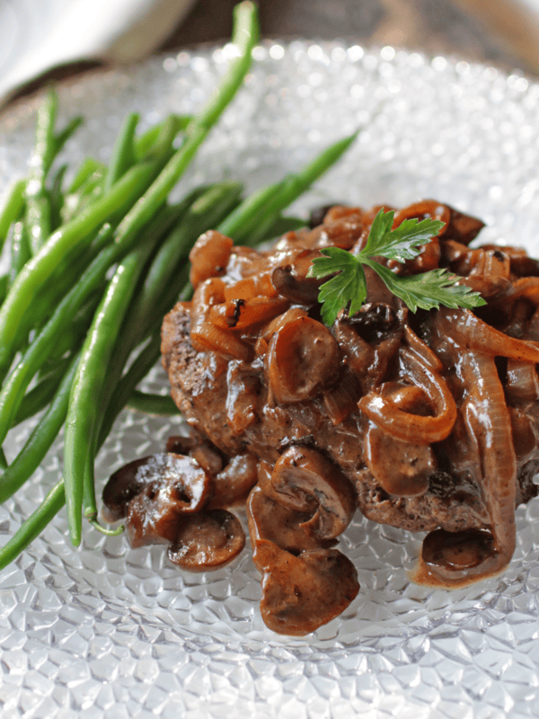 Salisbury Steak on a plate with green beans.