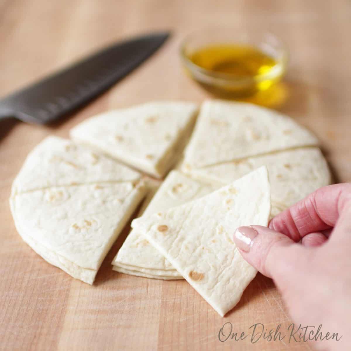 tortillas cut into wedges on a brown cutting board.