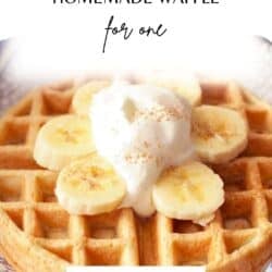 one belgian waffle on a plate topped with bananas and whipped cream.