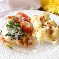 caprese chicken with roasted cauliflower on a white plate next to a yellow flower