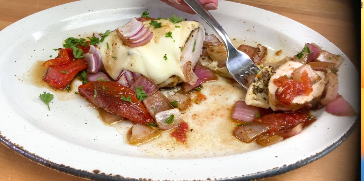 chicken caprese on a white plate with a fork on the side.