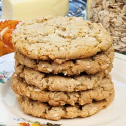 a stack of oatmeal cookies on a plate next to a stick of butter and a jar of oats