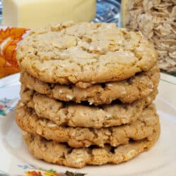 a stack of oatmeal cookies on a plate next to a stick of butter and a jar of oats