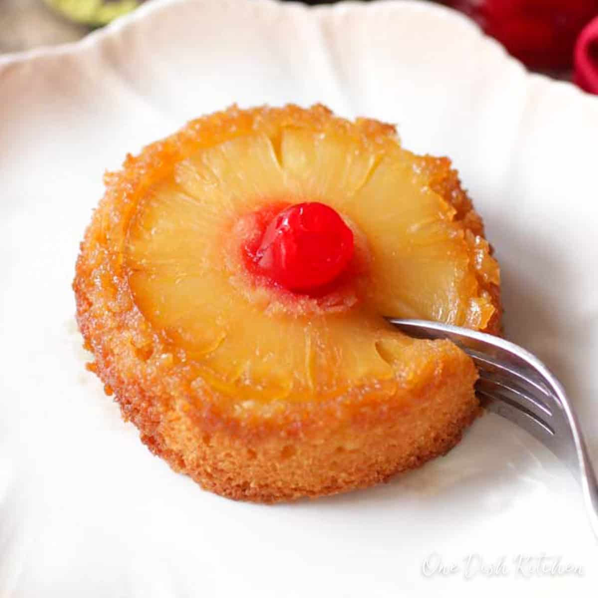 a small pineapple upside down cake with a fork on the side of the plate.
