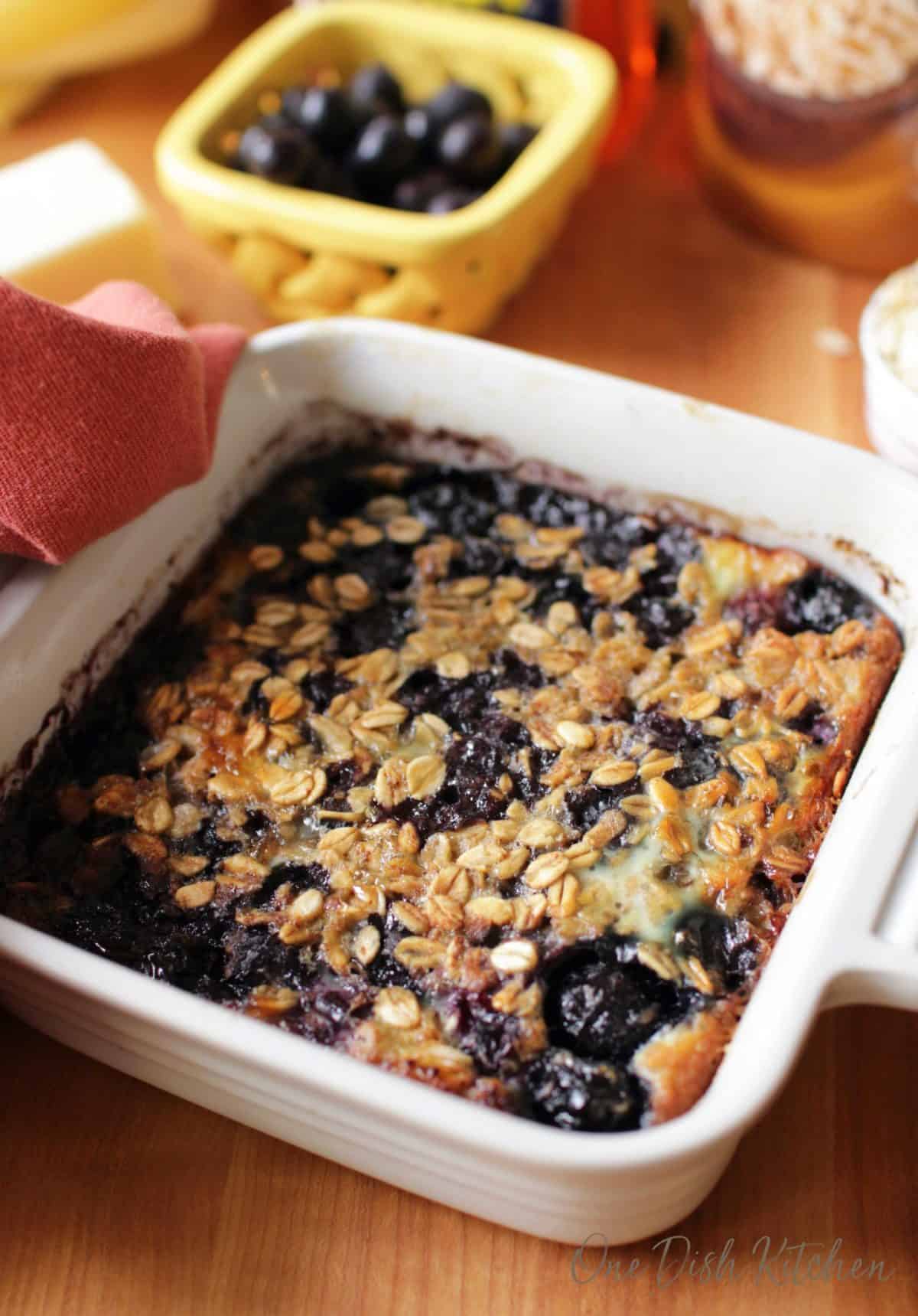 baked oatmeal with blueberries in a white square baking dish.