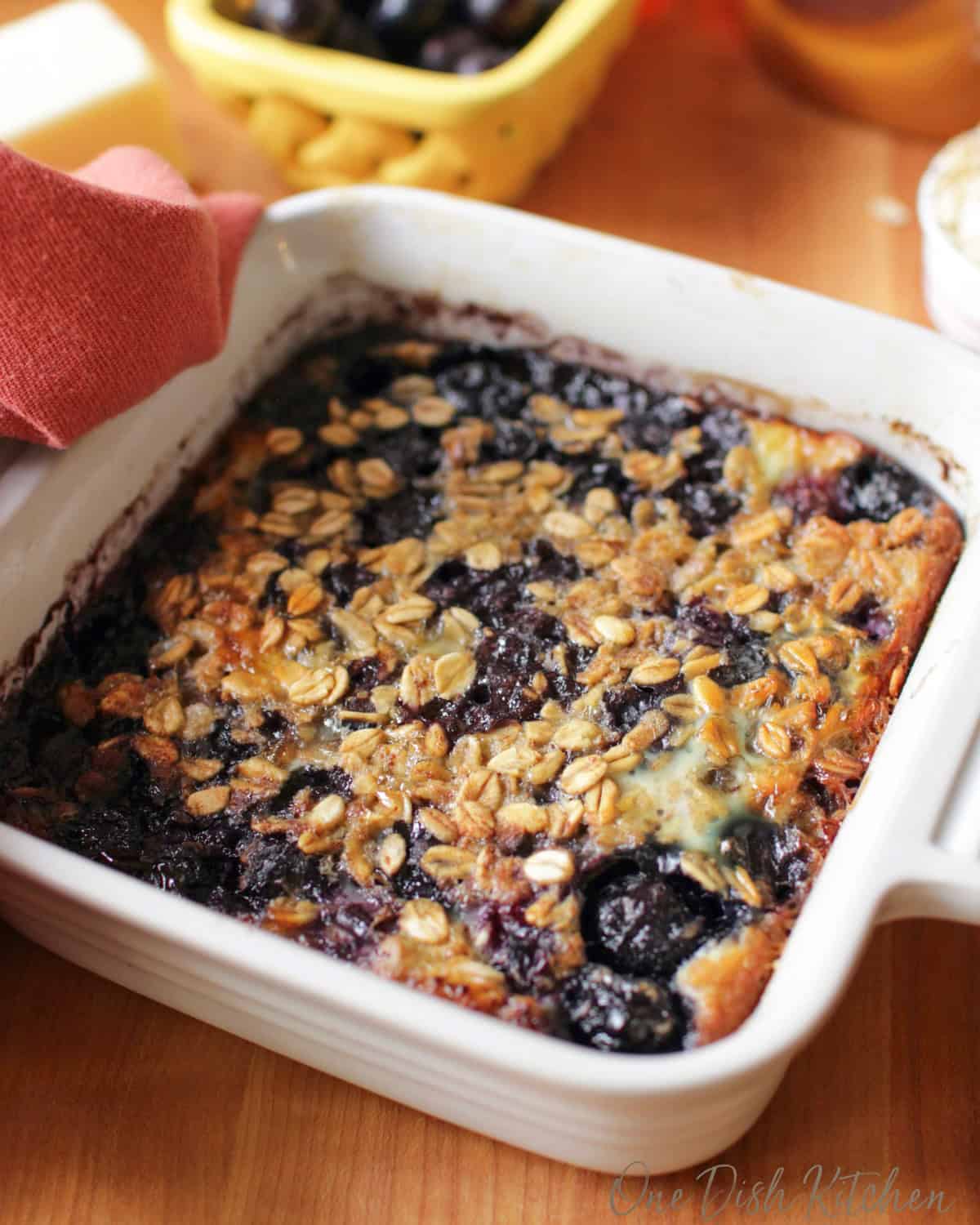 baked oatmeal with blueberries in a white square baking dish.