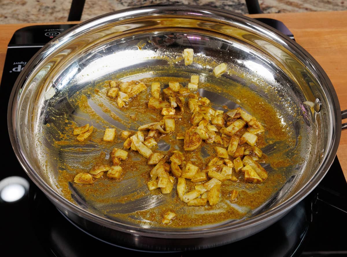 onions and garlic cooking in a skillet with curry powder and ginger