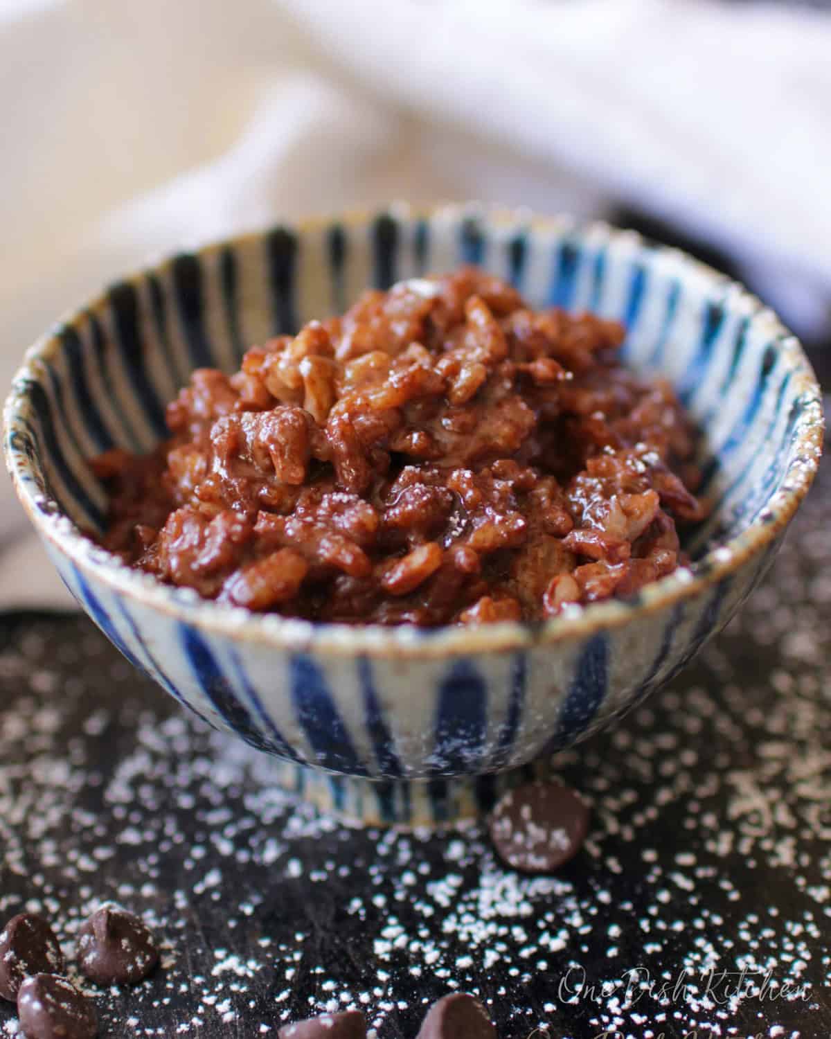a single serving chocolate rice pudding in a blue bowl.
