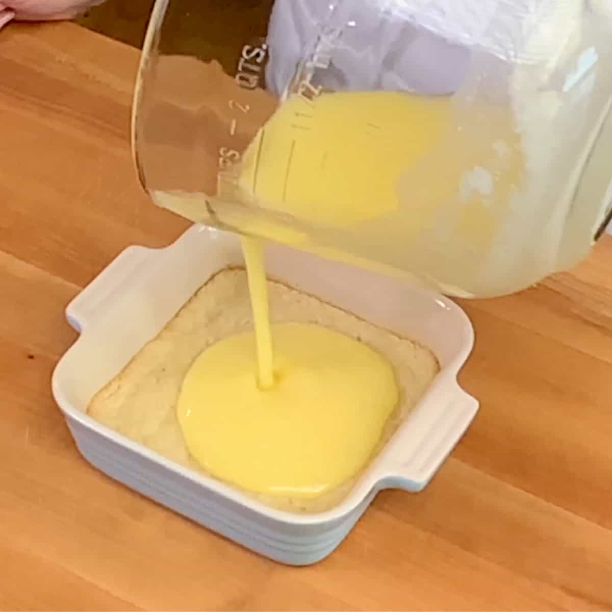 pouring lemon bar filling over the crust before baking