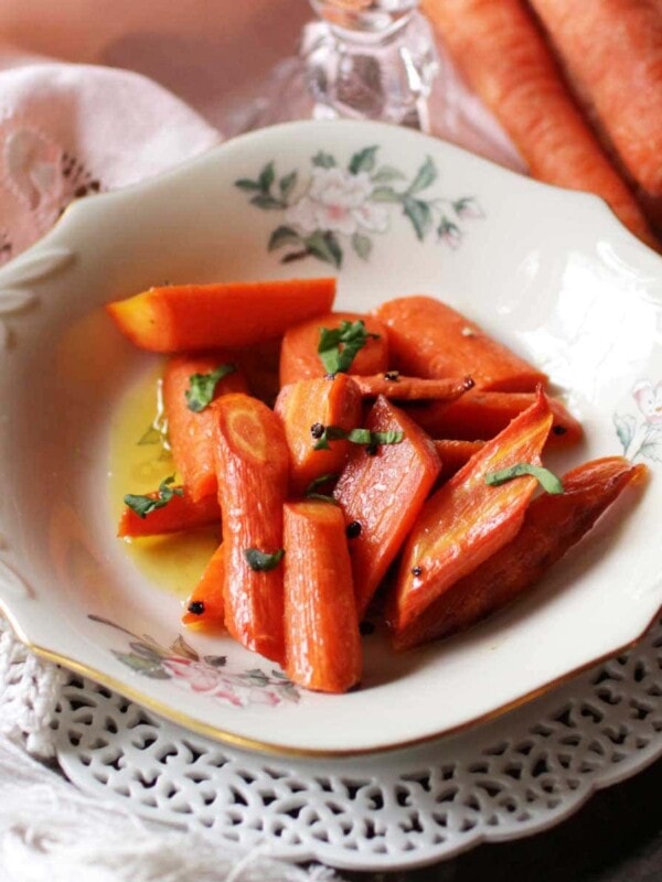 a white plate filled with roasted carrots topped with chopped parsley