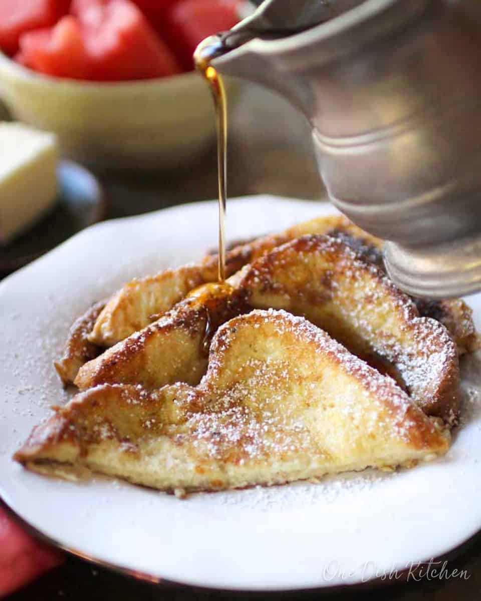 french toast on a white plate with syrup.