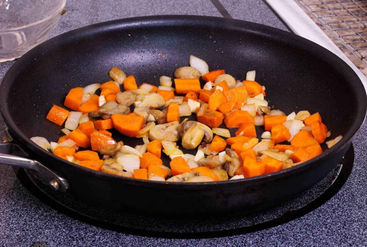 chopped onions, carrots, garlic, and mushrooms cooking in a skillet