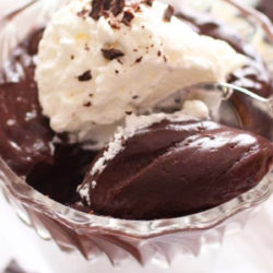 chocolate pudding in a small bowl topped with whipped cream and shaved chocolate.