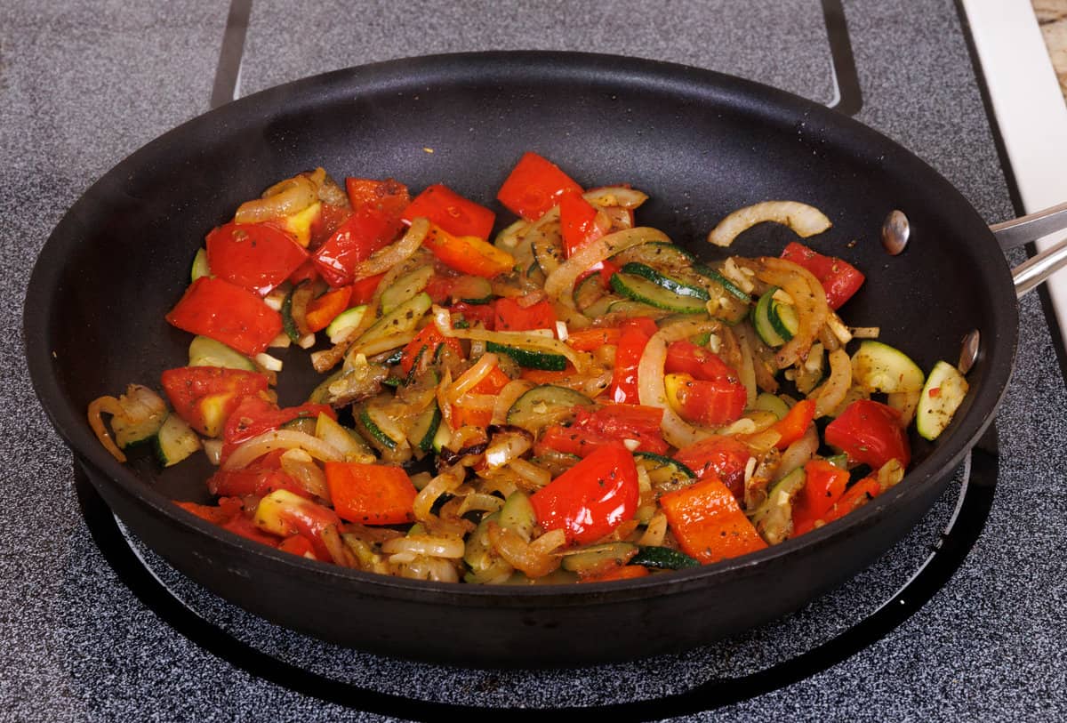 vegetables cooking in a frying pan.