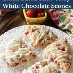 four strawberry scones on a white plate next to a bowl of strawberries.