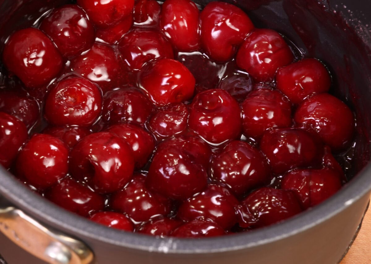 a small batch of cherry pie filling cooking in a small pot.