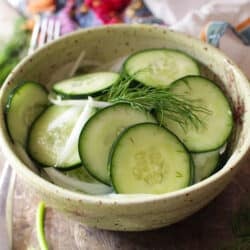cucumbers in a bowl with sliced onions and fresh dill.