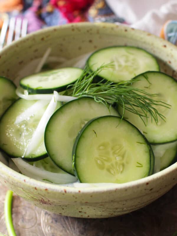 cucumbers in a bowl with sliced onions and fresh dill.