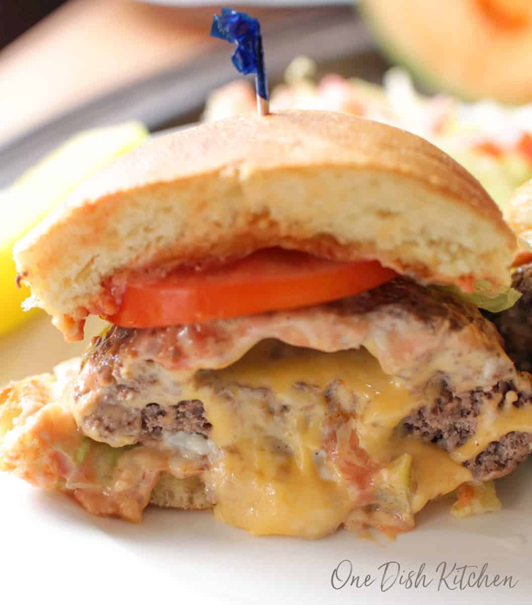 half of a juicy lucy on a plate with the melted cheese flowing out.