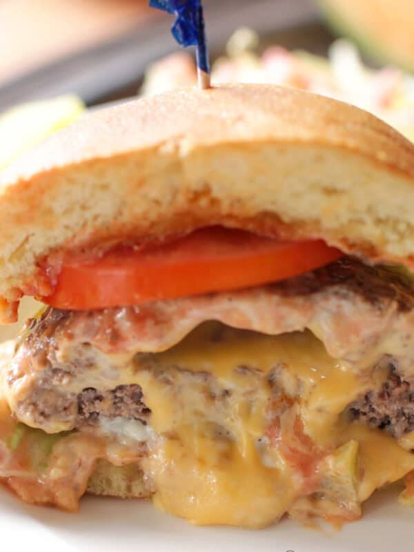 half of a juicy lucy on a plate with the melted cheese flowing out.