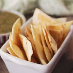 baked tortilla chips in a white dish next to a green napkin.