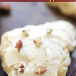 a scone topped with frosting and chopped pecans.