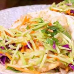 fish tacos on a plate with broccoli slaw on top.