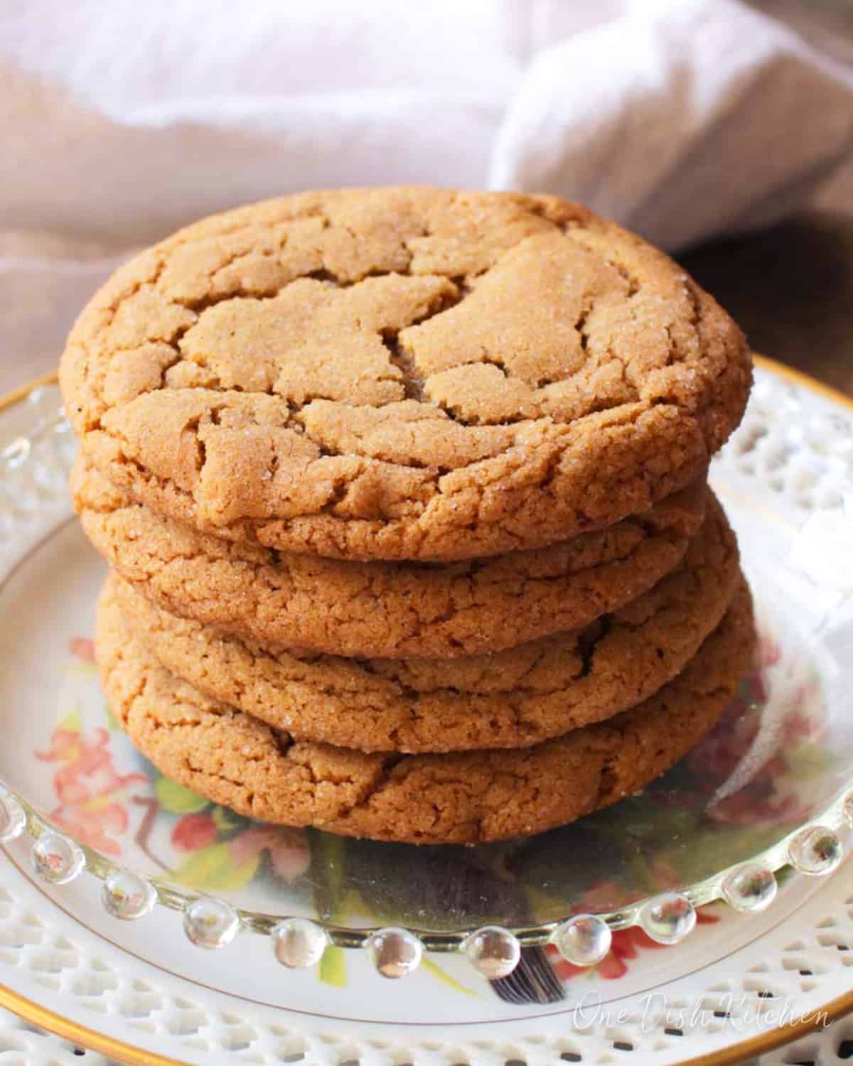 four ginger cookies stacked on a plate.