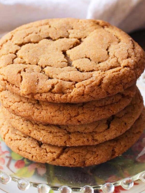 four ginger cookies stacked on a plate.